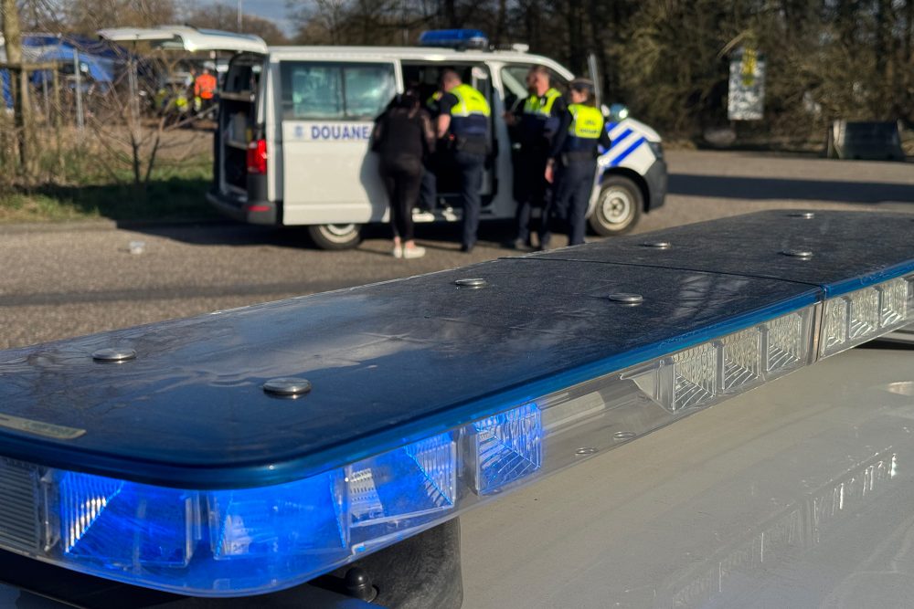 Im Vordergrund sieht man ein Blaulicht auf einem Fahrzeugdach, im Hintergrund sieht man ein Fahrzeug des Zolls mit mehreren Personen davor
