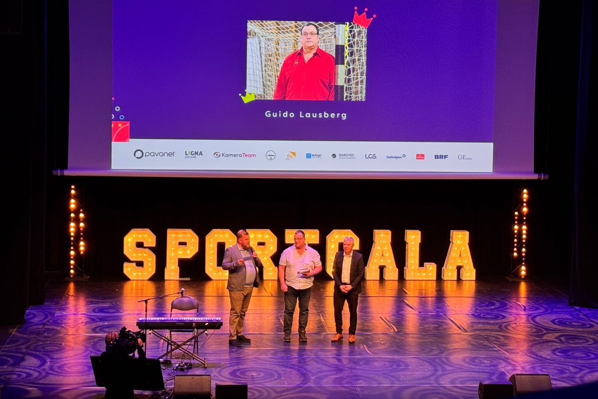 Preisträger Guido Lausberg mit Minister Gregor Freches und Moderator Christophe Ramjoie auf der Bühne, im Hintergrund bilden große Buchstaben das Wort Sportgala