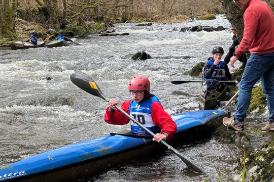 Einer der Wassersportler sitzt in seinem Kayak mit dem Paddel in den Händen
