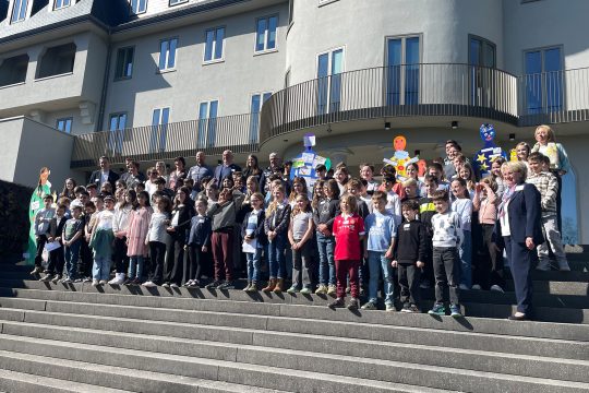 Gruppenbild der Kinder mit PDG-Vertretern und gebastelten Pappfiguren