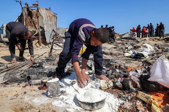 Nach einem israelischen Angriff sammelt ein Junge Mehlreste auf