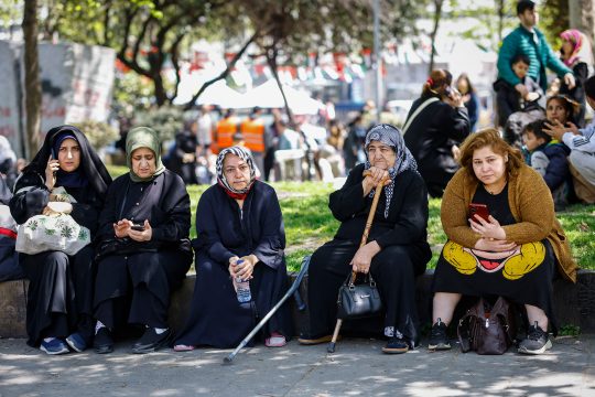 Mehrere Frauen sitzen am Rand einer Rasenfläche