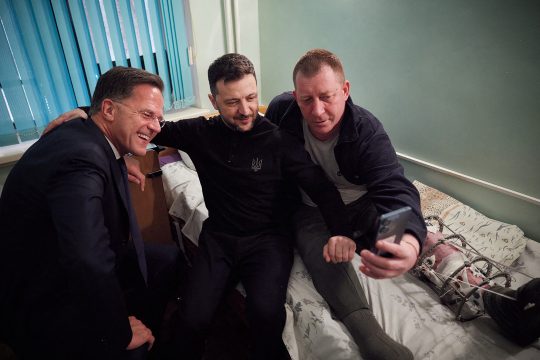 Mark Rutte und Wolodymyr Selenskyj machen ein Selfie mit einem verwundeten Soldaten