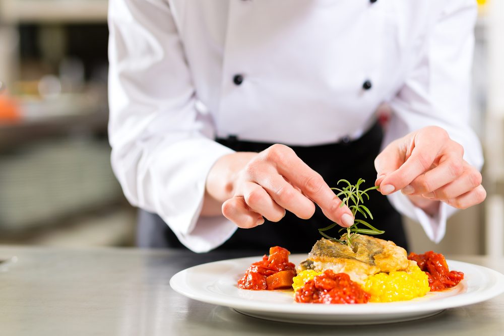 Köchin in Restaurant richtet Essen an
