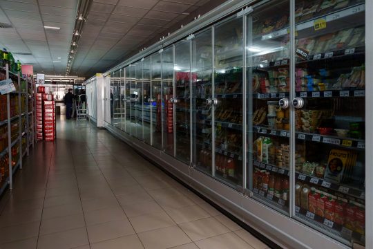 Ein Mitarbeiter steht neben ausgeschalteten Kühl- und Gefrierschränken