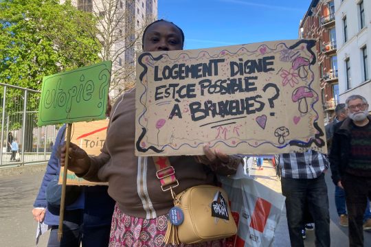 Protest in Brüssel für bezahlbaren Wohnraum: Demonstrantin mit Plakaten