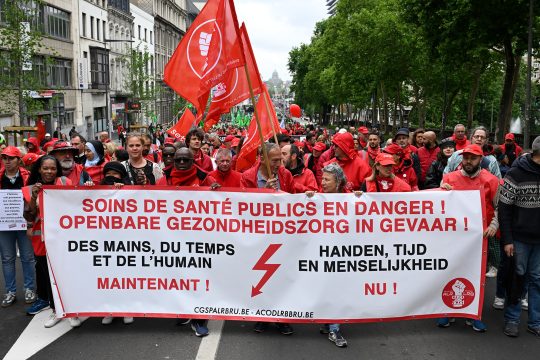 Demonstranten ziehen mit Fahnen und einem großen Transparent durch Brüssel