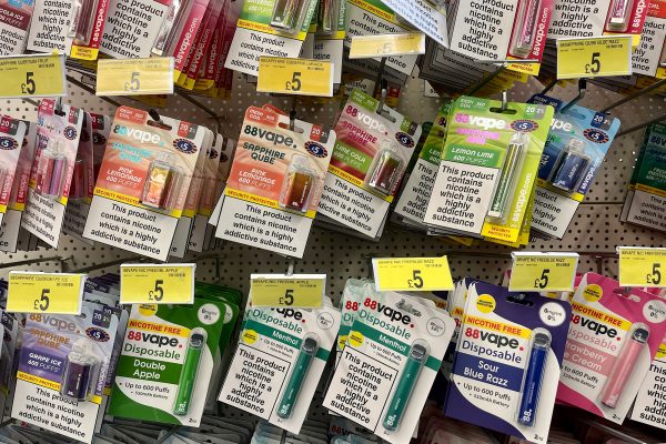 Eine Vielzahl von Einweg-E-Zigaretten mit unterschiedlichen Geschmacksrichtungen hängen an einem Regal