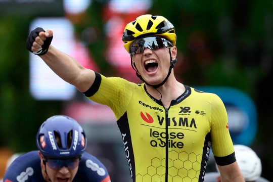 Der niederländische Radprofi Olav Kooij reckt einen Arm in die Höhe und jubelt