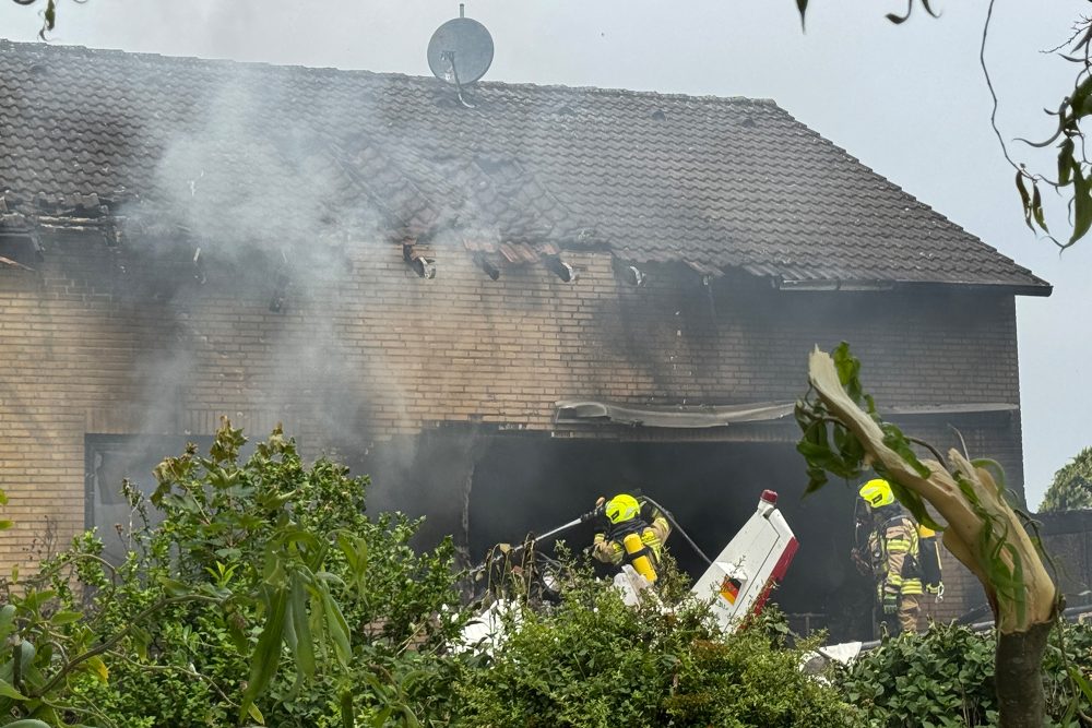 Feuerwehrleute arbeiten an der Absturzstelle, nachdem ein Flugzeug in das Wohnhaus gestürzt ist
