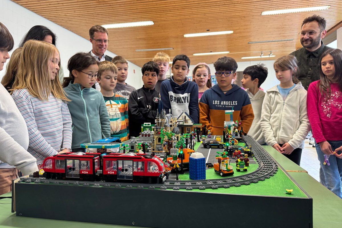 Grundschüler und weitere Projektteilnehmer stehen um das Lego-Stadtmodell von Aachen herum