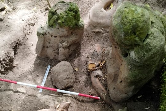 An der Ausgrabungsstätte liegen zwei Skulpturen in menschlicher Erscheinung auf dem Boden