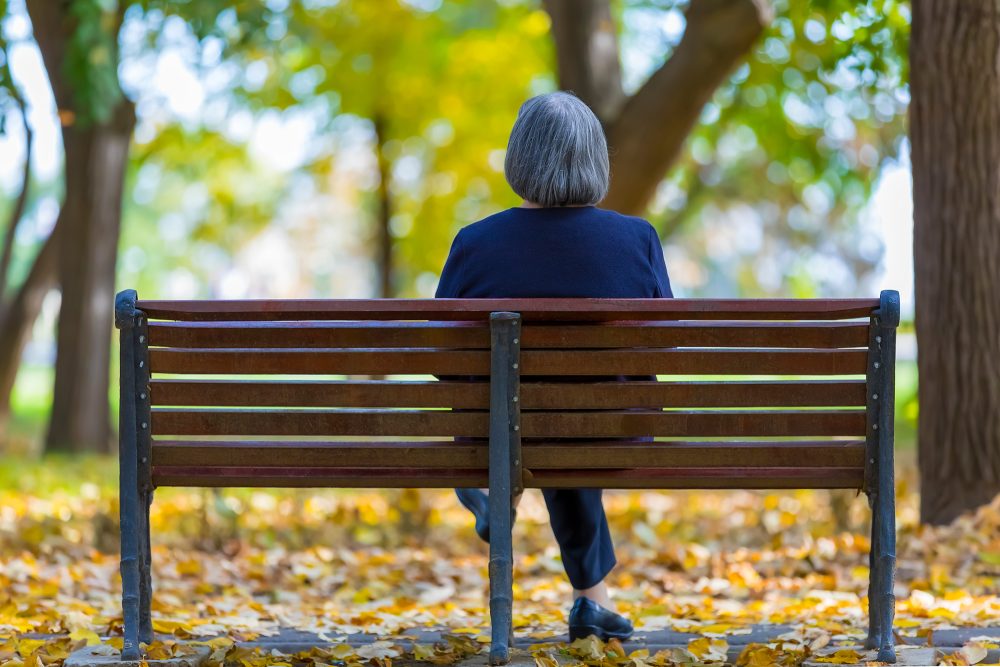 Seniorin auf einer Parkbank