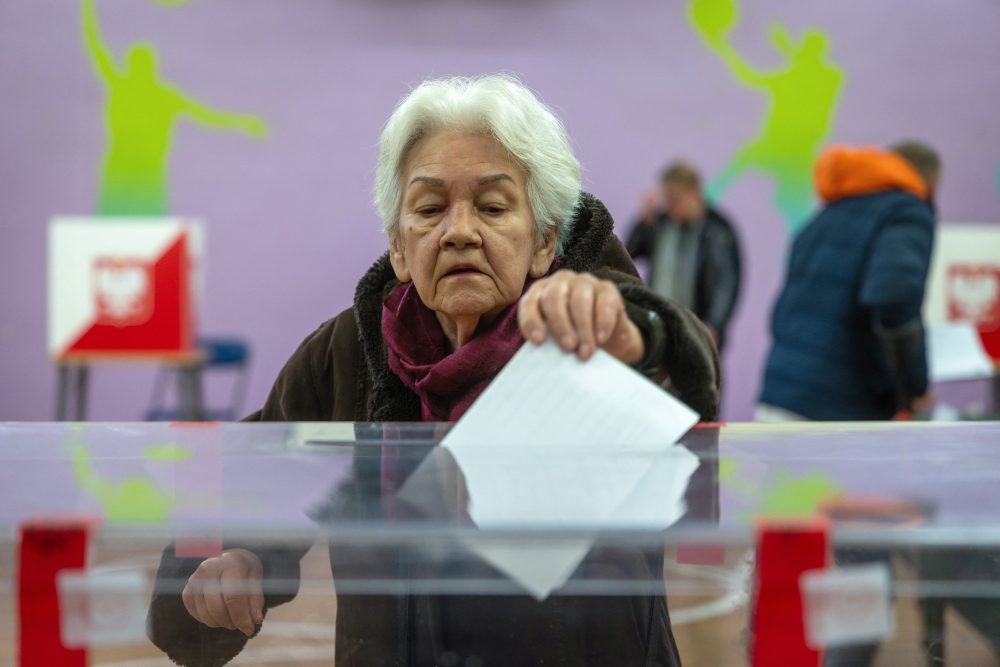 Eine Frau steckt ihren Stimmzettel in die Wahlurne in einem Wahlbüro in Warschau