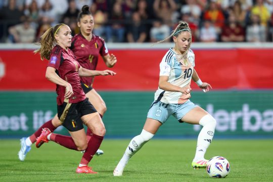 Eine spanische Spielerin kickt den Ball, während zwei belgische Spielerinnen hinter ihr herlaufen