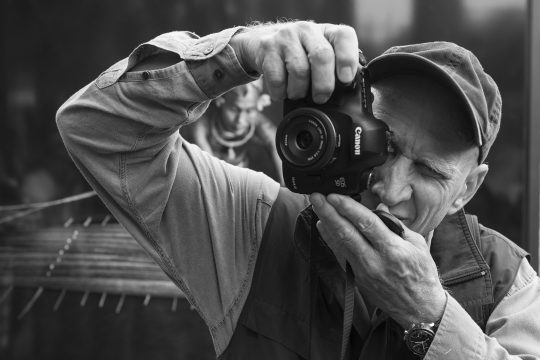 Sebastião Ribeiro Salgado hält eine Kamera in den Händen und schaut durch den Sucher