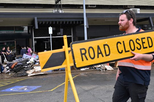 Aufräumarbeiten in der Stadt Taree - Mann trägt eine Straßenabsperrung