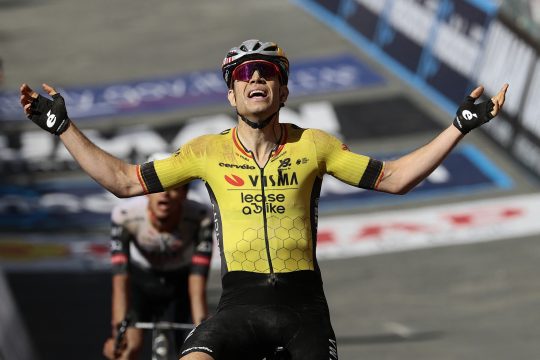Wout van Aert reißt die Arme zum Jubeln in die Höhe, als er über die Ziellinie fährt