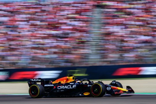 Max Verstappen im Red Bull, im Hintergrund sieht man verschwommen die Zuschauer auf der Tribüne