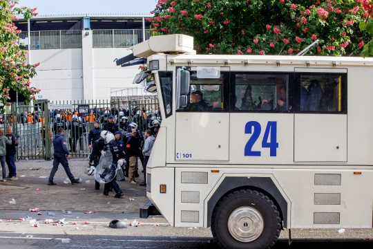 Wasserwerfer der Polizei, im Hintergrund Polizisten und Fans vor dem Stadion