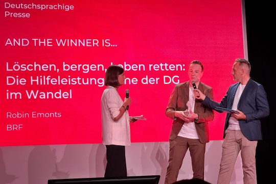 Robin Emonts nimmt den Preis entgegen und äußert sich auf der Bühne am Mikrofon