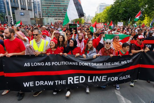Demonstranten in Brüssel halten ein Banner vor sich, in englischer Sprache steht dort unter anderem übersetzt "Wir ziehen die rote Linie für Gaza"