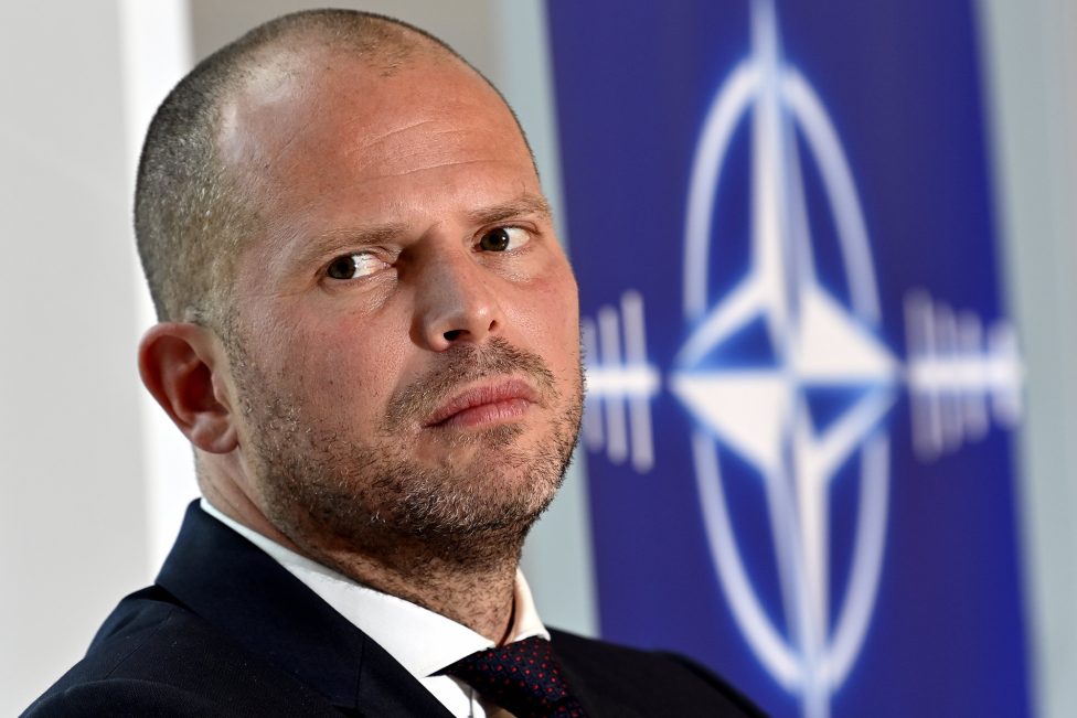 Verteidigungsminister Theo Francken, hinter ihm ein Banner mit einem nachempfundenen Logo der Nato