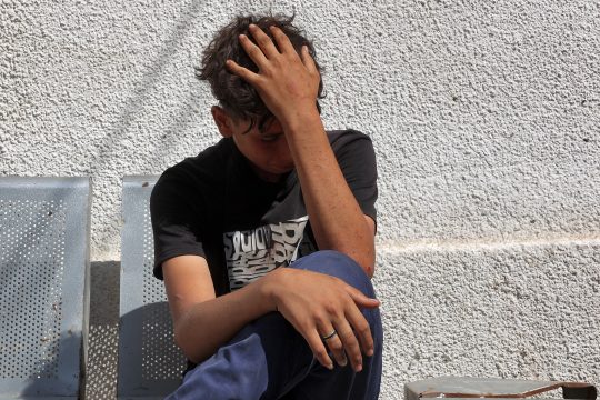 Ein palästinensischer Junge sitzt vor dem Al-Shifa-Krankenhaus in Gaza-Stadt und hält sich niedergeschlagen den Kopf