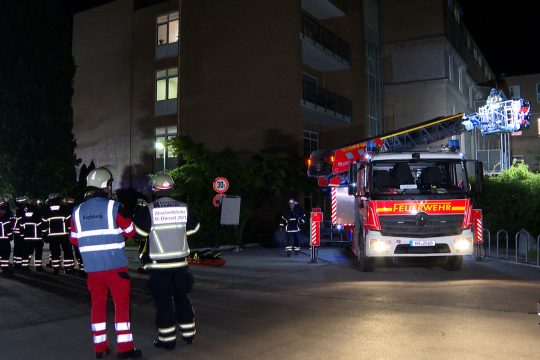 Feuerwehrleute und ein Feuerwehrdrehleiterfahrzeug vor dem Krankenhaus