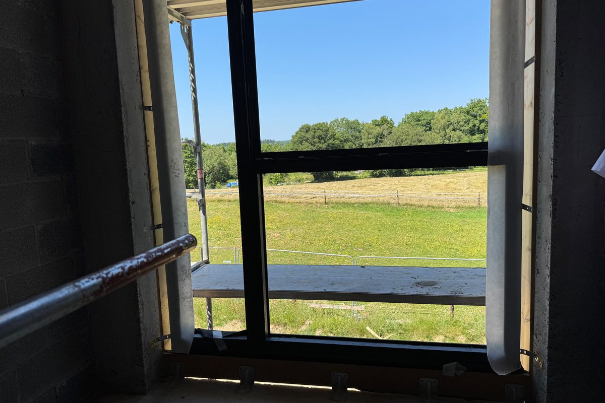 Die Schulbaustelle von innen mit Blick durch ein Fenster auf eine Wiese