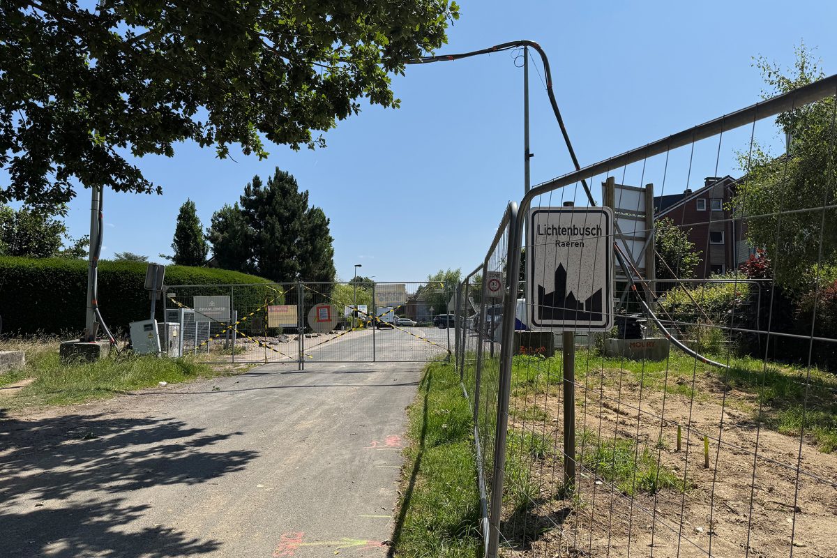 Blick von der Baustelle aus durch den Zaun in Richtung Straße