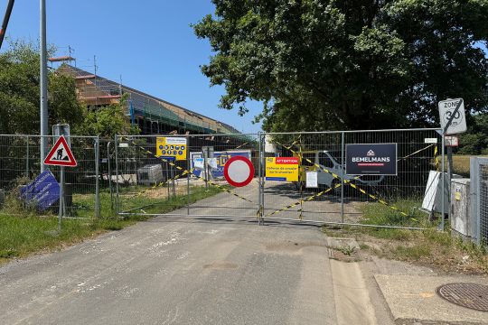 Vorne der Baustellenzaun, im Hintergrund dann das im Bau befindliche Gebäude des Schulneubaus