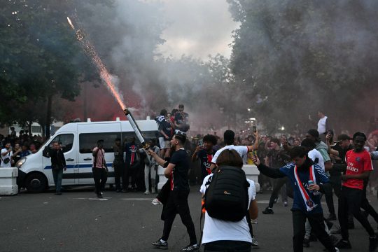 Fans von Paris Saint-Germain zünden ein Feuerwerk neben einem Polizeifahrzeug