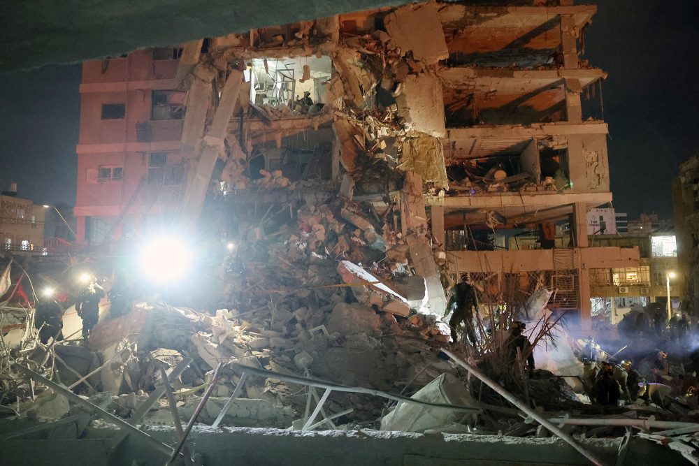 Rettungskräfte stehen vor einem Gebäude, das nach einem iranischen Raketenangriff in der israelischen Stadt Bat Yam stark beschädigt wurde