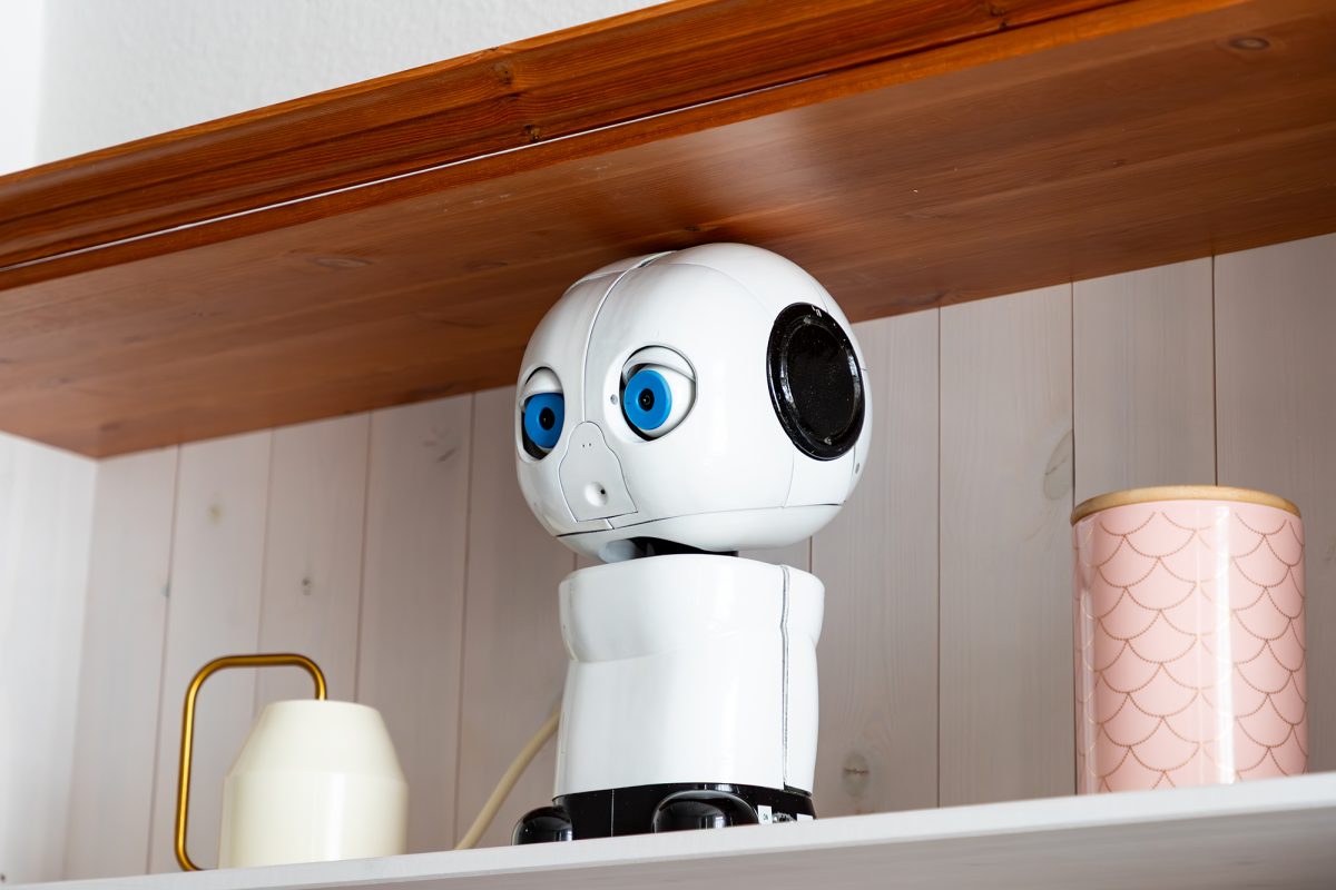Kleiner Roboter mit blauen Kameraaugen und schwarzen Lautsprecherohren