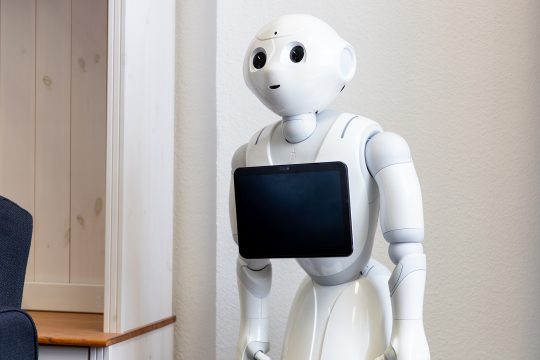 Roboter, der mit Kopf und Armen menschenähnlich ist, hat ein Tablet an der Brust