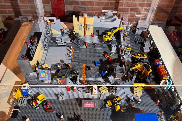 Ein Lego-Modell in einem Glaskasten zeigt eine Baustelle mit Baggern und Bauarbeitern