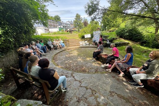 Projekt-Teilnehmerinnen sitzen zusammen in einem Halbrund im Garten