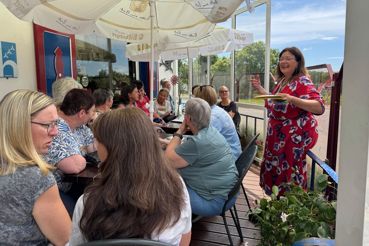 Elke Drosson und Projektteilnehmerinnen auf der Terrasse des Hotels an Tischen mit aufgespannten Sonnenschirmen