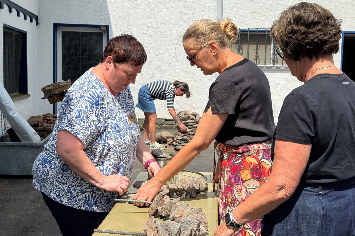 Teilnehmerinnen vor einem Tisch mit Steinen, die zum Basteln verwendet werden