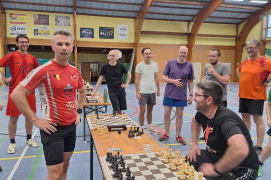 François Van Lishout und weitere Spieler stehen um die Spieltische herum