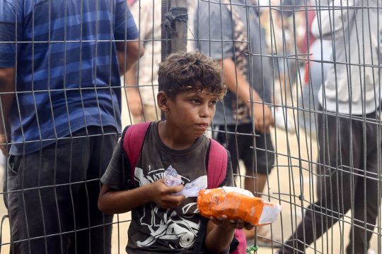 ein palästinensischer Junge hält ein Hilfspaket