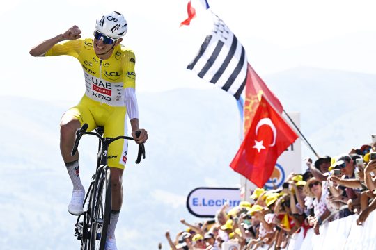 Tadej Pogacar reckt den Arm in die Höhe und jubelt