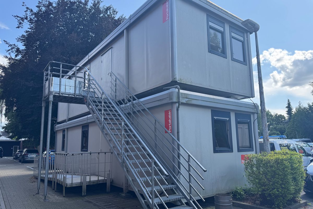 Mehrere Container, teilweise aufeinandergestapelt, die als Behelfsmaßnahme auf dem Parkplatz aufgestellt wurden
