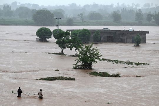 Männer fischen in der Nähe eines überschwemmten Hauses in Rawalpindi, Pakistan