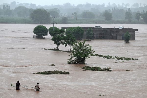 Männer fischen in der Nähe eines überschwemmten Hauses in Rawalpindi, Pakistan