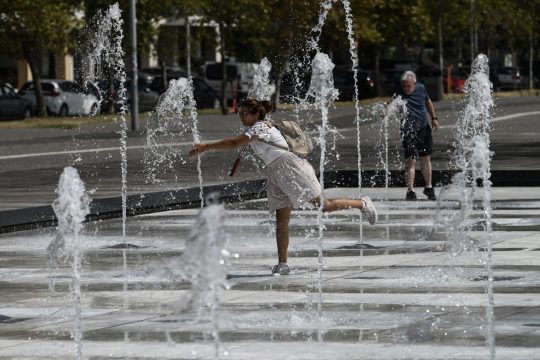 Passanten kühlen sich im Springbrunnen ab