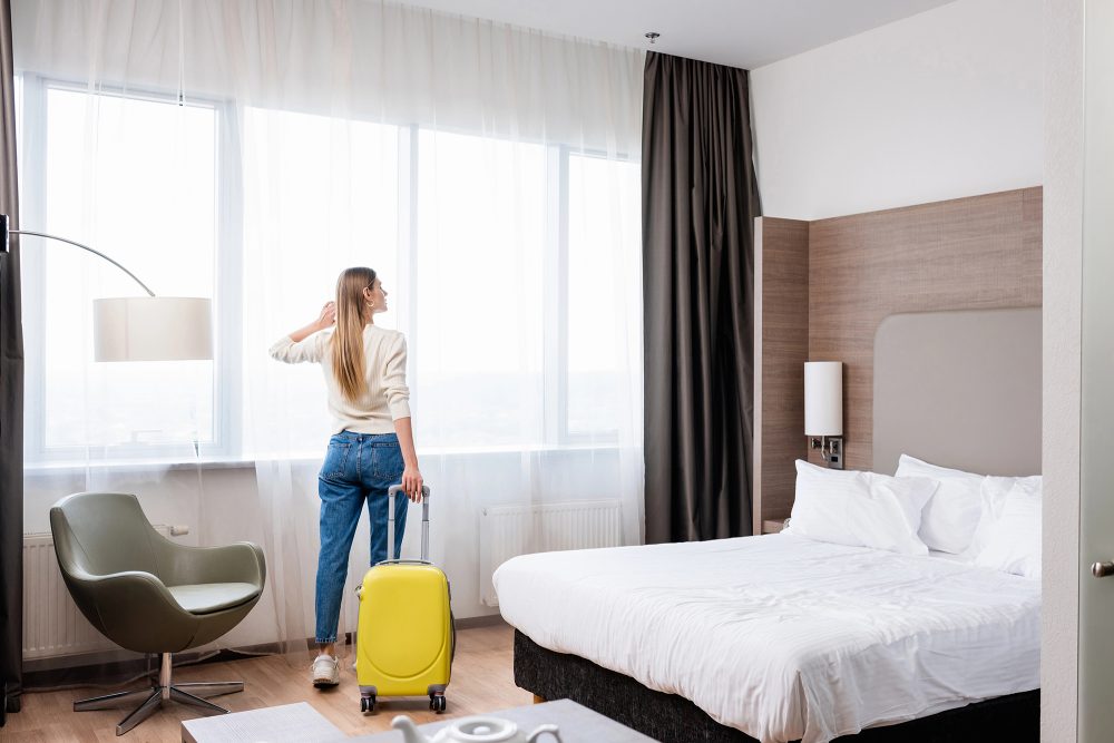 Touristin mit Koffer im Hotelzimmer
