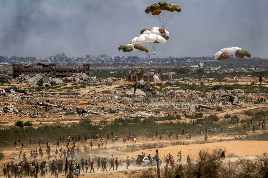 Palästinenser eilen zum Ort des Geschehens, als Hilfsgüterpaletten aus einem Militärflugzeug über Nuseirat im zentralen Gazastreifen abgeworfen werden