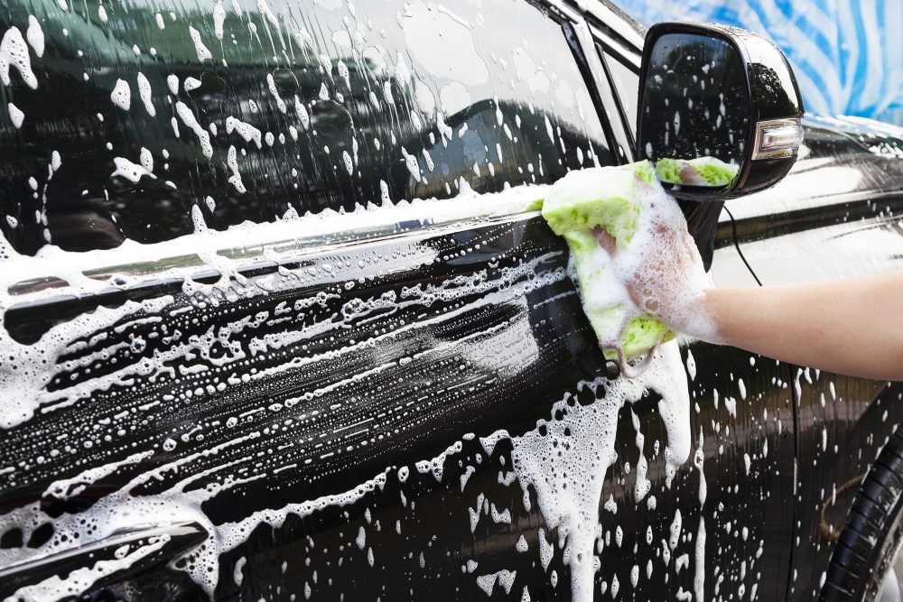 Hand mit Schwamm beim Autowaschen
